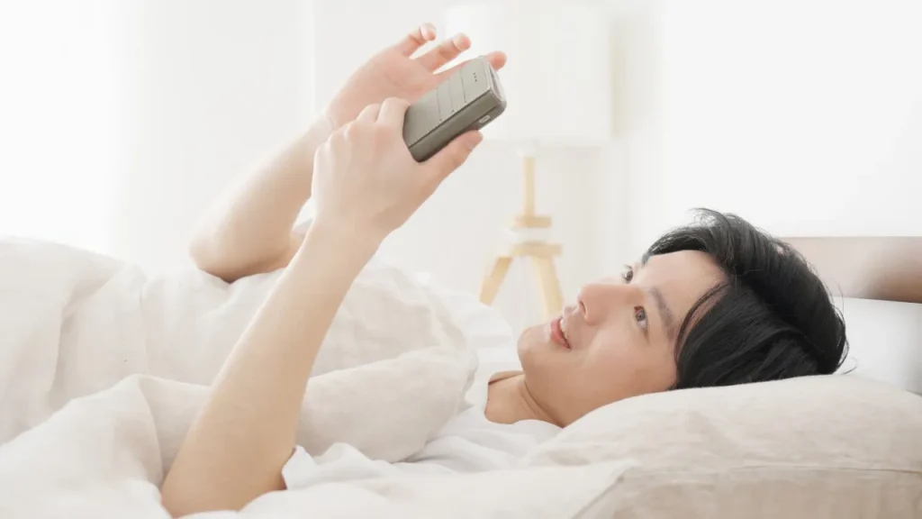 寝ながらスマホを見る男性